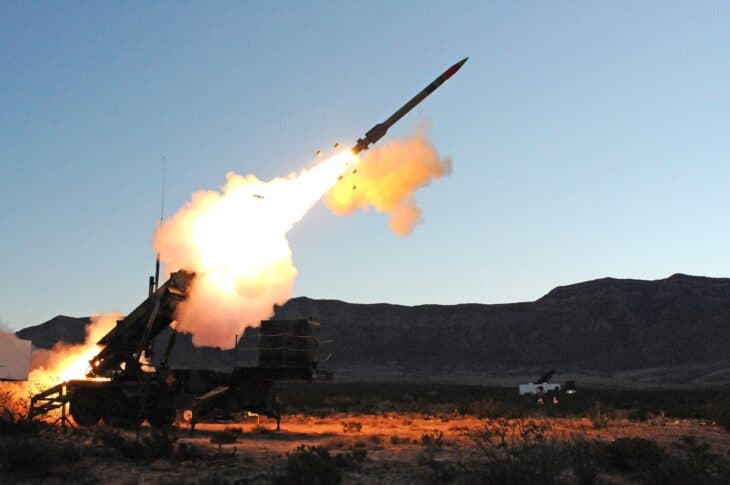 Patriot missile launching from its truck-mounted launcher at dusk with a bright rocket plume