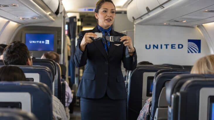 A United flight attendant holding up a seatbelt buckle during the safety demonstration