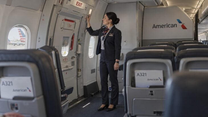 An American flight attendant checking the emergency exit door in the cabin