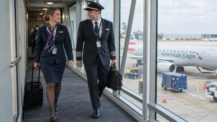 An Envoy flight attendant and pilot walking down a jet bridge with roller bags