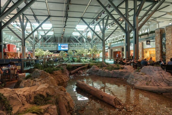 Indoor landscaped water feature with rocks and logs in the Vancouver International Airport terminal