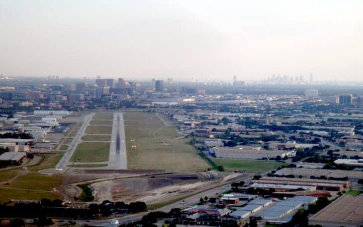 Aerial view of Addison Airport with its runway and the Dallas skyline behind
