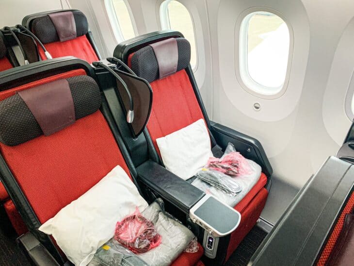Red Japan Airlines premium economy seats beside a window on a Boeing 787-9
