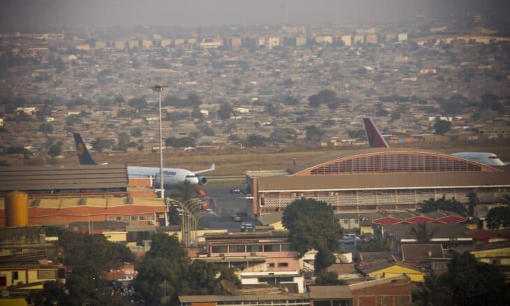 Aerial view of Quatro de Fevereiro Airport in Luanda with an airliner at the terminal and the city behind