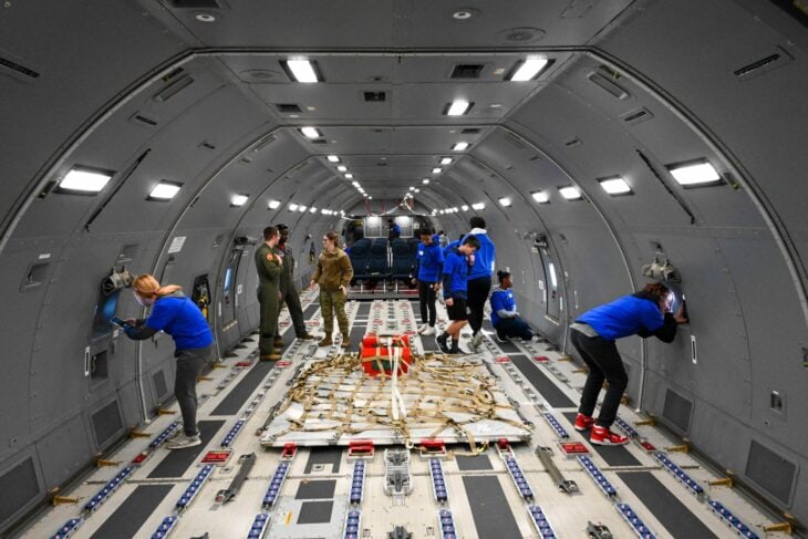 Airmen working around a cargo pallet inside the long open cabin of a KC-46 Pegasus