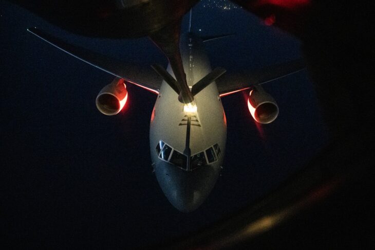 KC-46 Pegasus seen head-on from a boom pod window while receiving fuel from a KC-135 at night