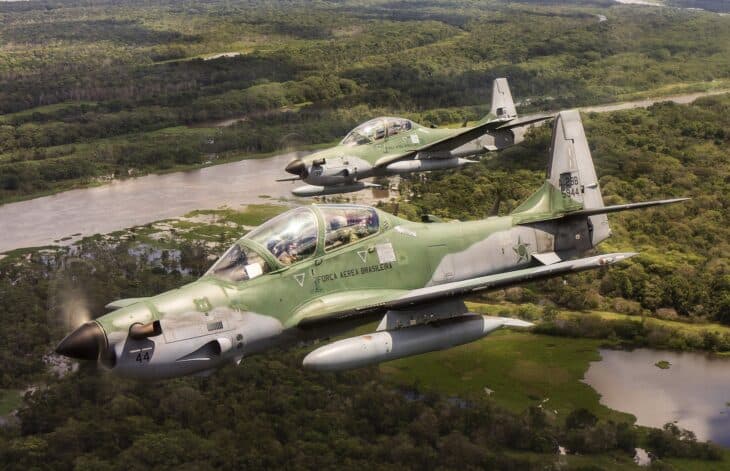 Two Brazilian Air Force A-29 Super Tucanos flying over the Amazon rainforest and a river