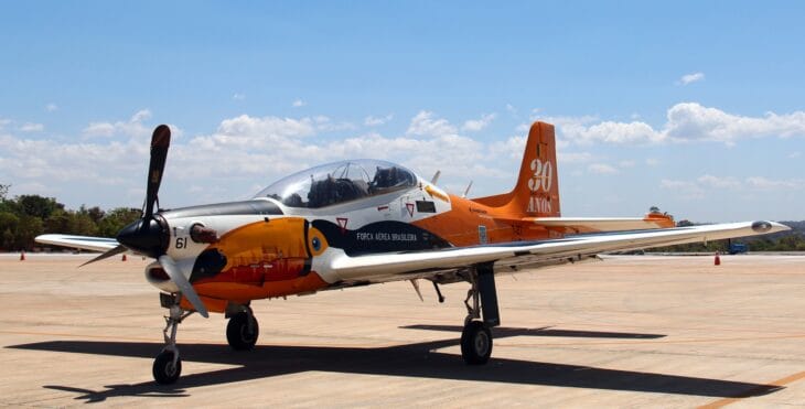 Brazilian Air Force T-27 Tucano trainer in orange and white commemorative paint on the ramp
