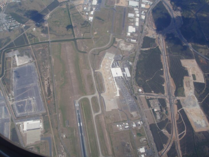 Aerial view of Brisbane Airport's international terminal and runways from an aircraft window