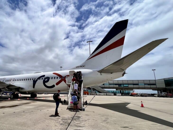 Passengers boarding a Rex Boeing 737 by air stairs on the apron at Brisbane Airport's domestic terminal