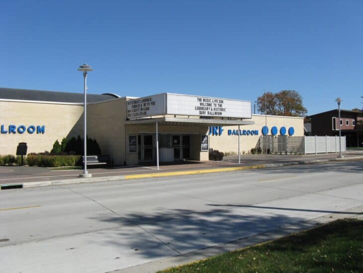 The Surf Ballroom's cream brick front and marquee under a blue sky in Clear Lake, Iowa