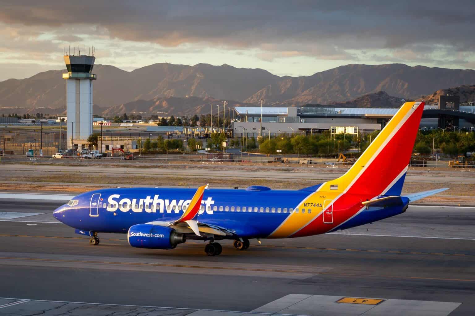 Southwest Airlines Boeing 737 taxiing at Hollywood Burbank Airport at dusk with the control tower and mountains behind