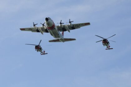 Coast Guard HC-130 Hercules flying in formation with two Coast Guard helicopters over the water