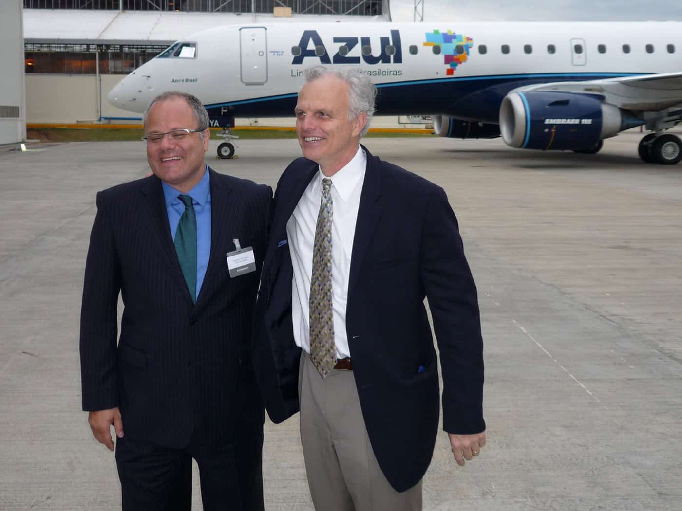 David Neeleman smiling beside an executive on the ramp, with an Azul Embraer 195 behind them