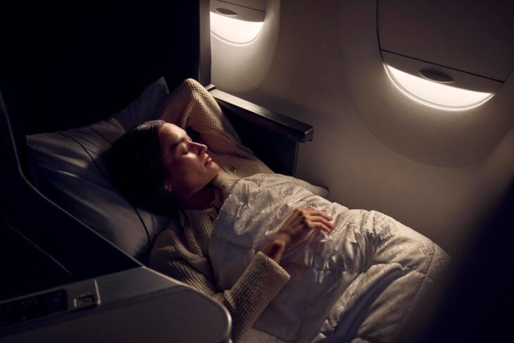 Passenger asleep under a duvet in a lie-flat Delta One seat on a Delta Airbus A350-900
