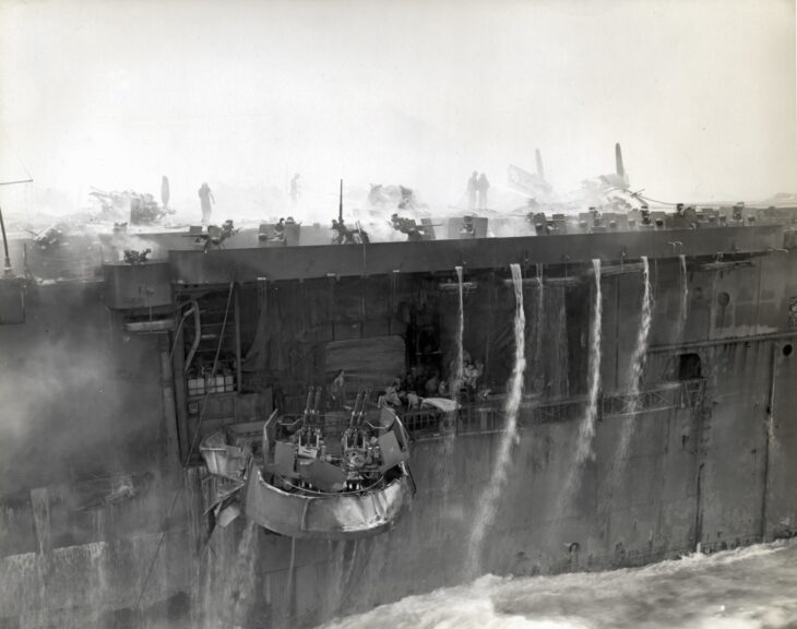 Smoke streaks down the side of USS Bunker Hill (CV-17) after two kamikaze hits off Okinawa on May 11, 1945