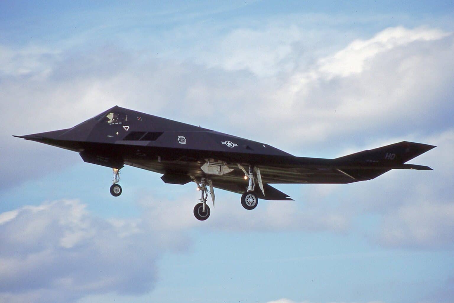 F-117A Nighthawk 86-0823 on approach with landing gear down against a cloudy sky