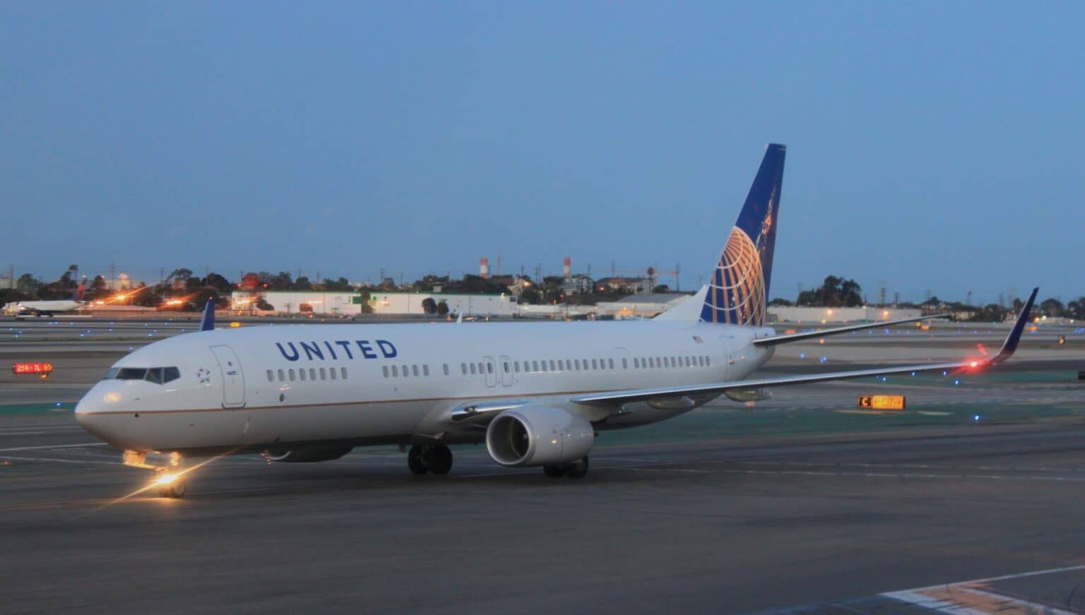 United Airlines Boeing 737-800 taxiing at dawn with its tail and horizontal stabilizer silhouetted against the sky
