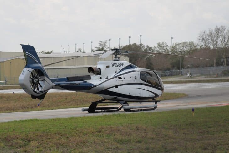 Eurocopter EC130 B4 helicopter N130PF parked on grass with its tail rotor and engine cowling in view