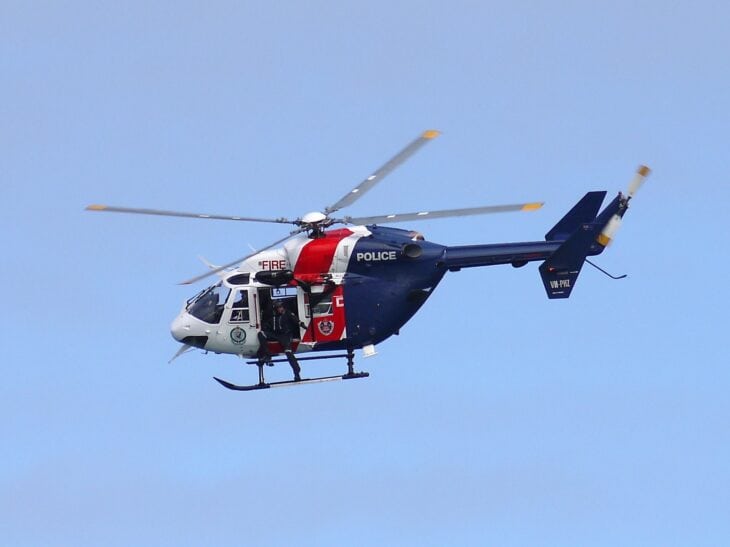Blue and white Highway Patrol BK-117 B2 helicopter in flight against a blue sky