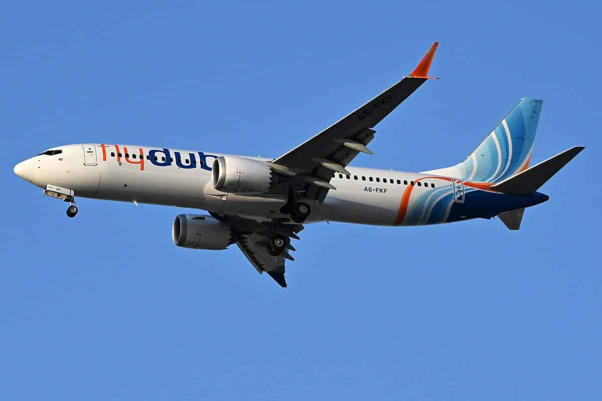 flydubai Boeing 737 MAX 8 A6-FKF in flight with landing gear down, seen from below against a blue sky