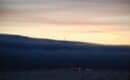 Fog bank over San Francisco Bay at dusk with an airliner on approach
