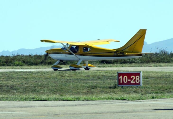 Yellow and white Glasair Sportsman 2+2 kit aircraft ZU-FIL taxiing on a grass-lined runway