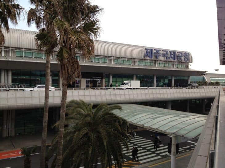 Terminal building and entrance of Jeju International Airport with palm trees in front
