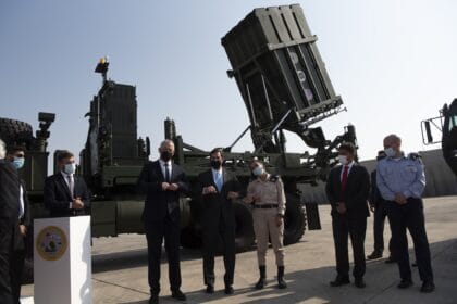 Iron Dome launcher with its Tamir interceptor tubes raised on an Israeli air base, with officials standing in front