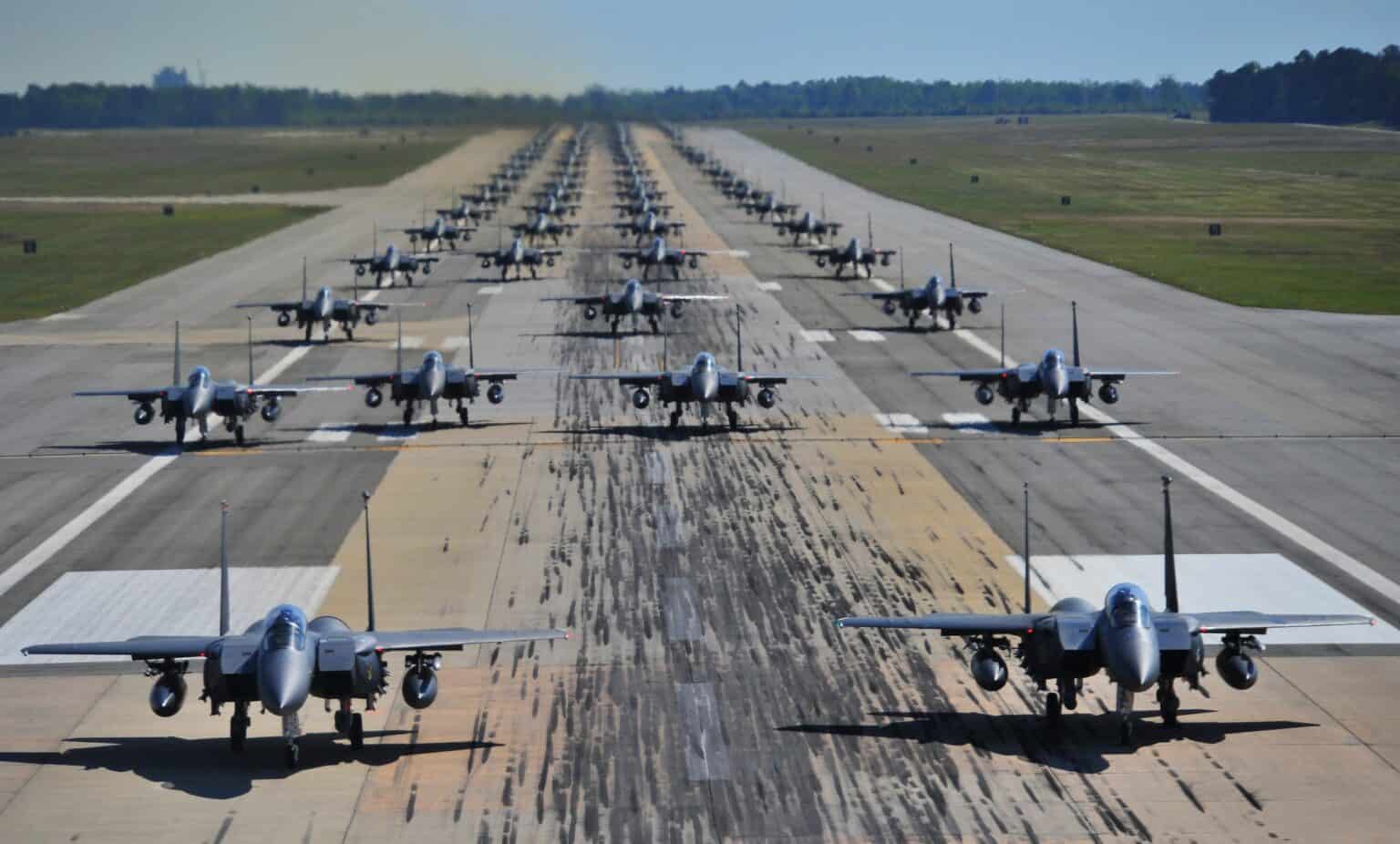Dozens of US Air Force F-15E Strike Eagles taxiing nose to tail down a runway in an elephant walk at Seymour Johnson Air Force Base