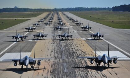 Dozens of US Air Force F-15E Strike Eagles taxiing nose to tail down a runway in an elephant walk at Seymour Johnson Air Force Base