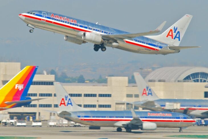American Airlines Boeing 737-800 in the old polished-metal livery climbing out of Los Angeles with two more American jets on the ramp below