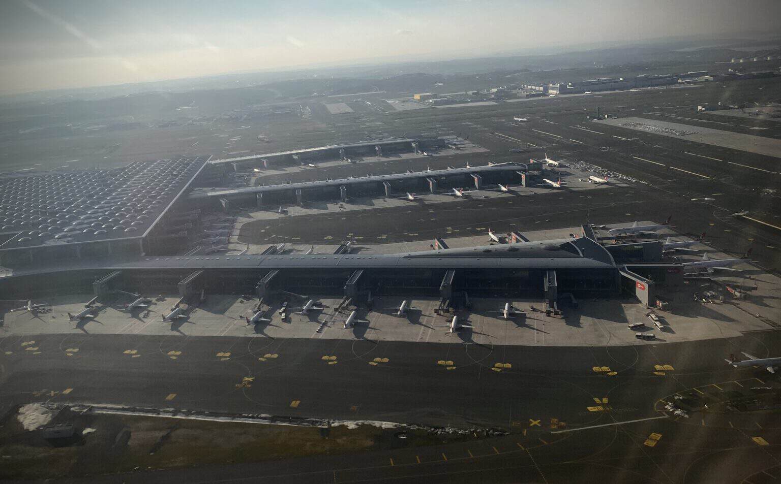 Aerial view of the Istanbul Airport terminal and its piers with parked airliners under a hazy gray sky