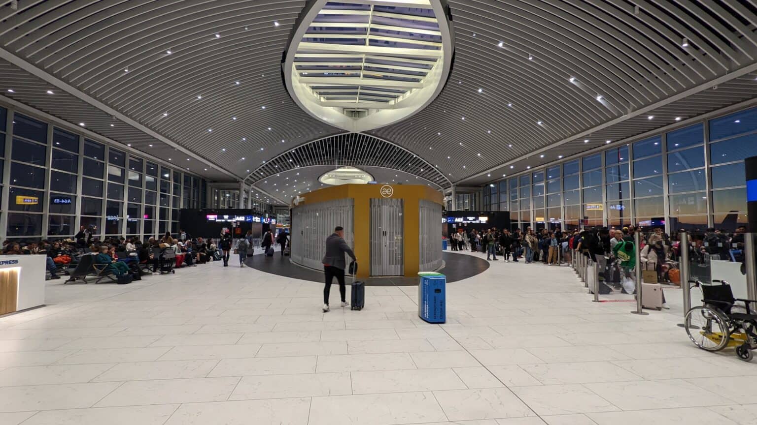 Travelers waiting in the wide Terminal A hall at Rome Fiumicino airport