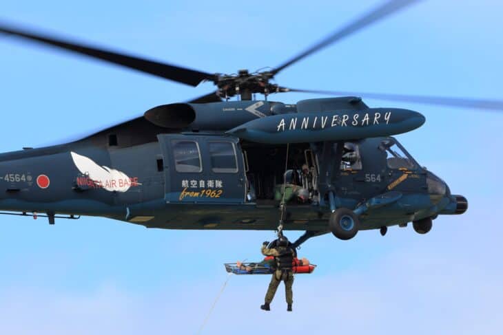 JASDF Mitsubishi UH-60J rescue helicopter lowering a rescuer on a hoist