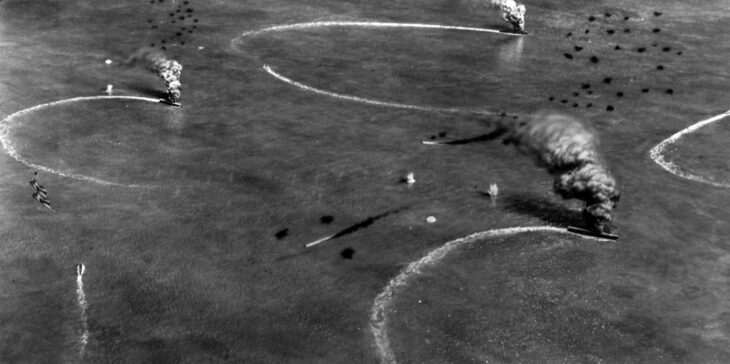 Aerial view of Kaga, Akagi and Soryu maneuvering under American air attack at Midway, with smoke rising from one carrier