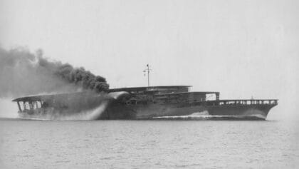Japanese aircraft carrier Akagi in 1927 with smoke streaming from its funnel and three stepped flight decks at the bow