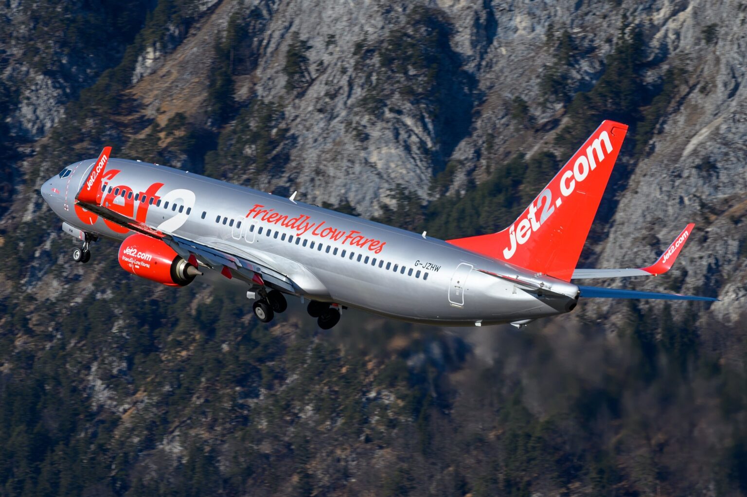 Jet2 Boeing 737-800 in red and silver livery climbing away over mountains