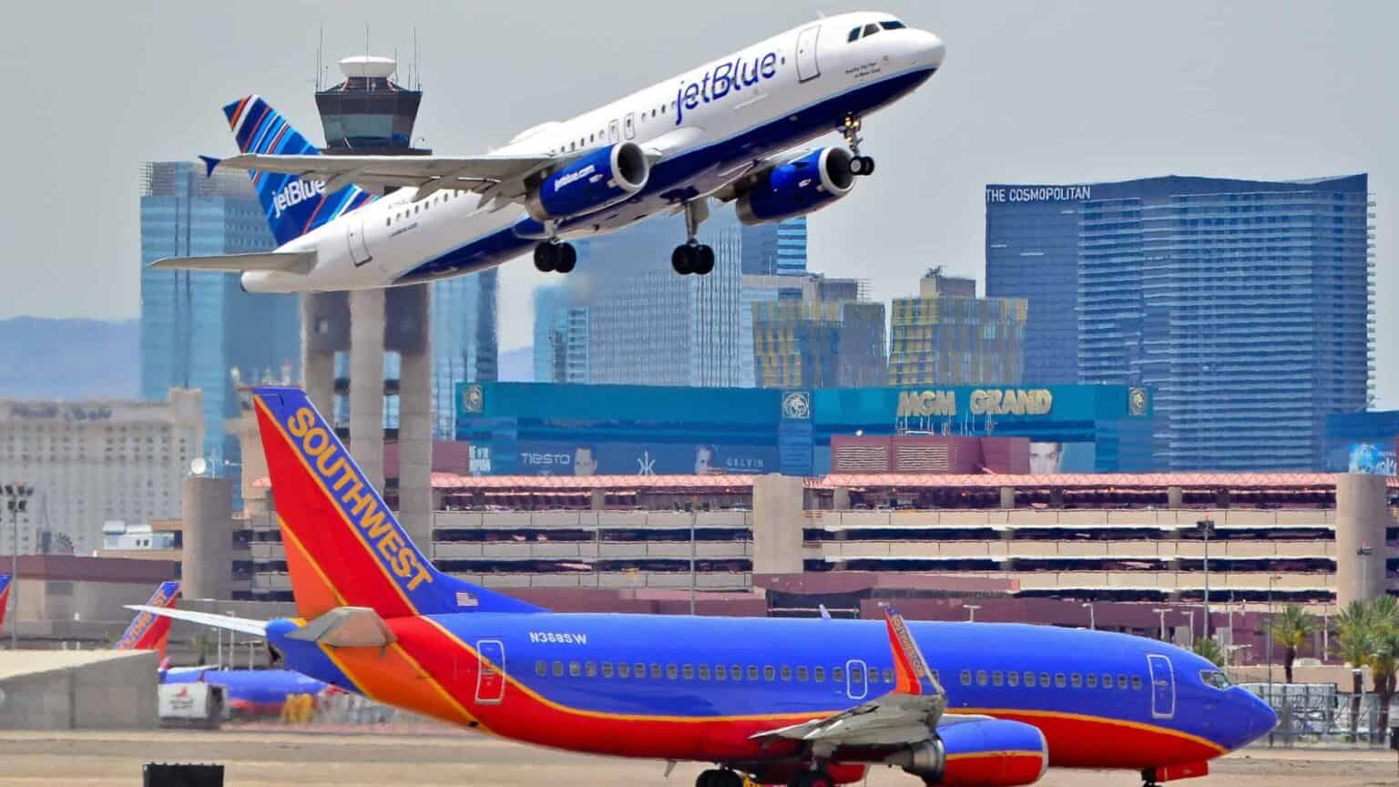 JetBlue Airbus A320 climbing out over a Southwest Boeing 737 on the ground at Las Vegas with the Strip behind