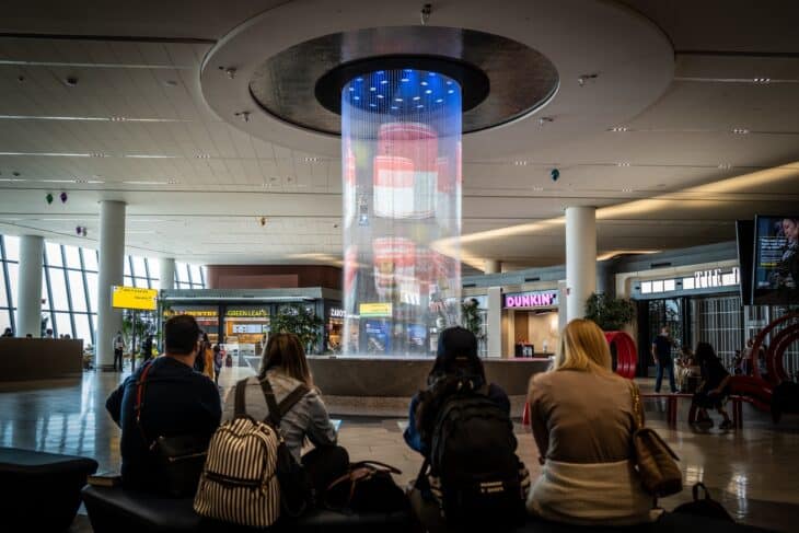 Travelers seated around the illuminated water feature in LaGuardia Terminal B
