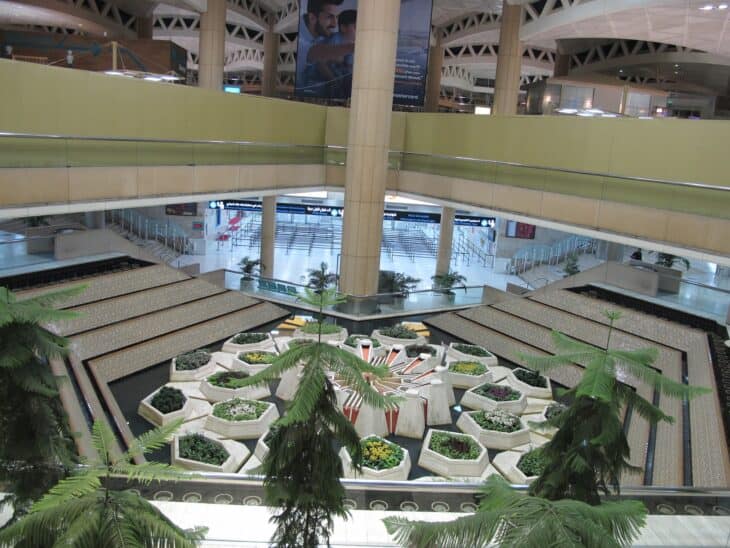 Central hall of the King Khalid International Airport terminal in Riyadh with an indoor garden and upper-level walkways