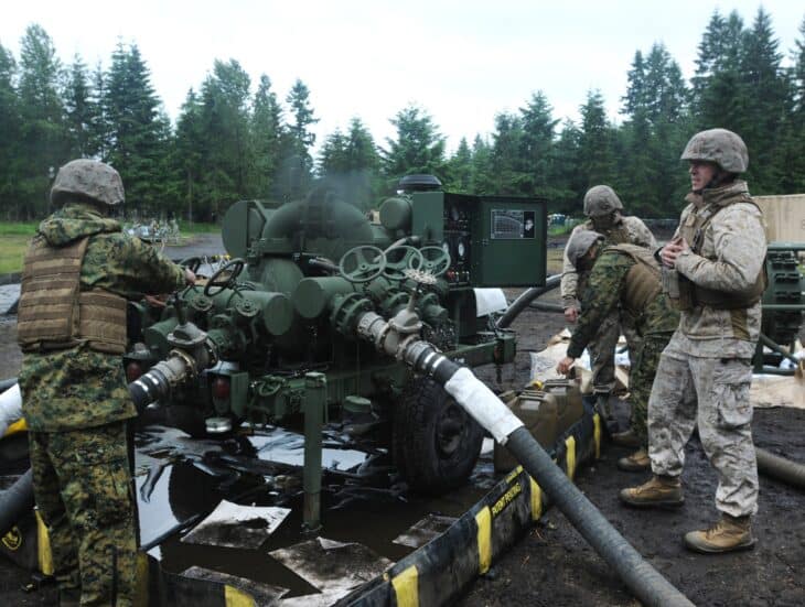 Soldiers firing a howitzer in a forest clearing at Joint Base Lewis-McChord