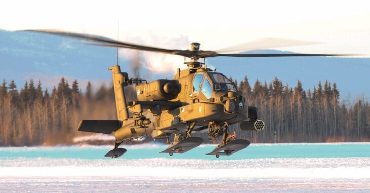 AH-64 Apache helicopter landing in snow near spruce forest at Fort Wainwright