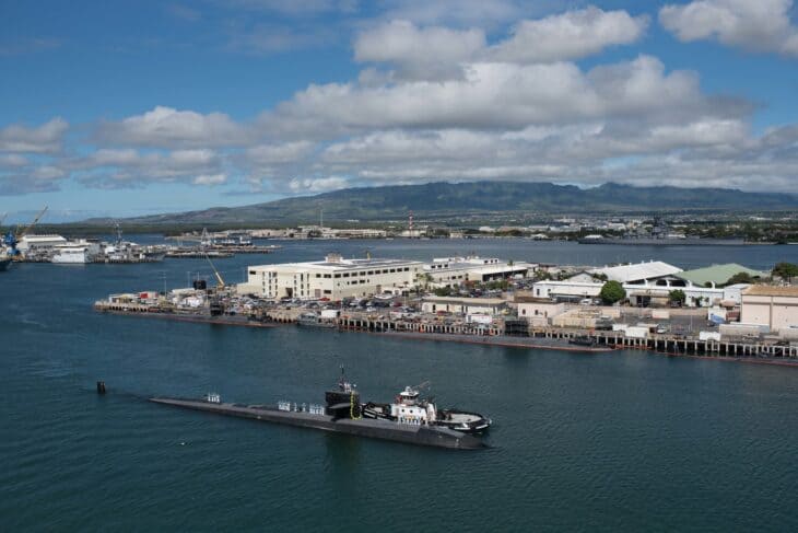 Attack submarine USS Bremerton on the surface entering Pearl Harbor with the naval base and mountains behind
