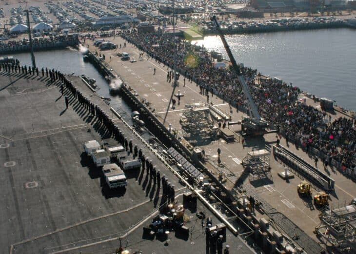 Sailors man the rails of USS Enterprise as it approaches a pier crowded with families at Naval Station Norfolk