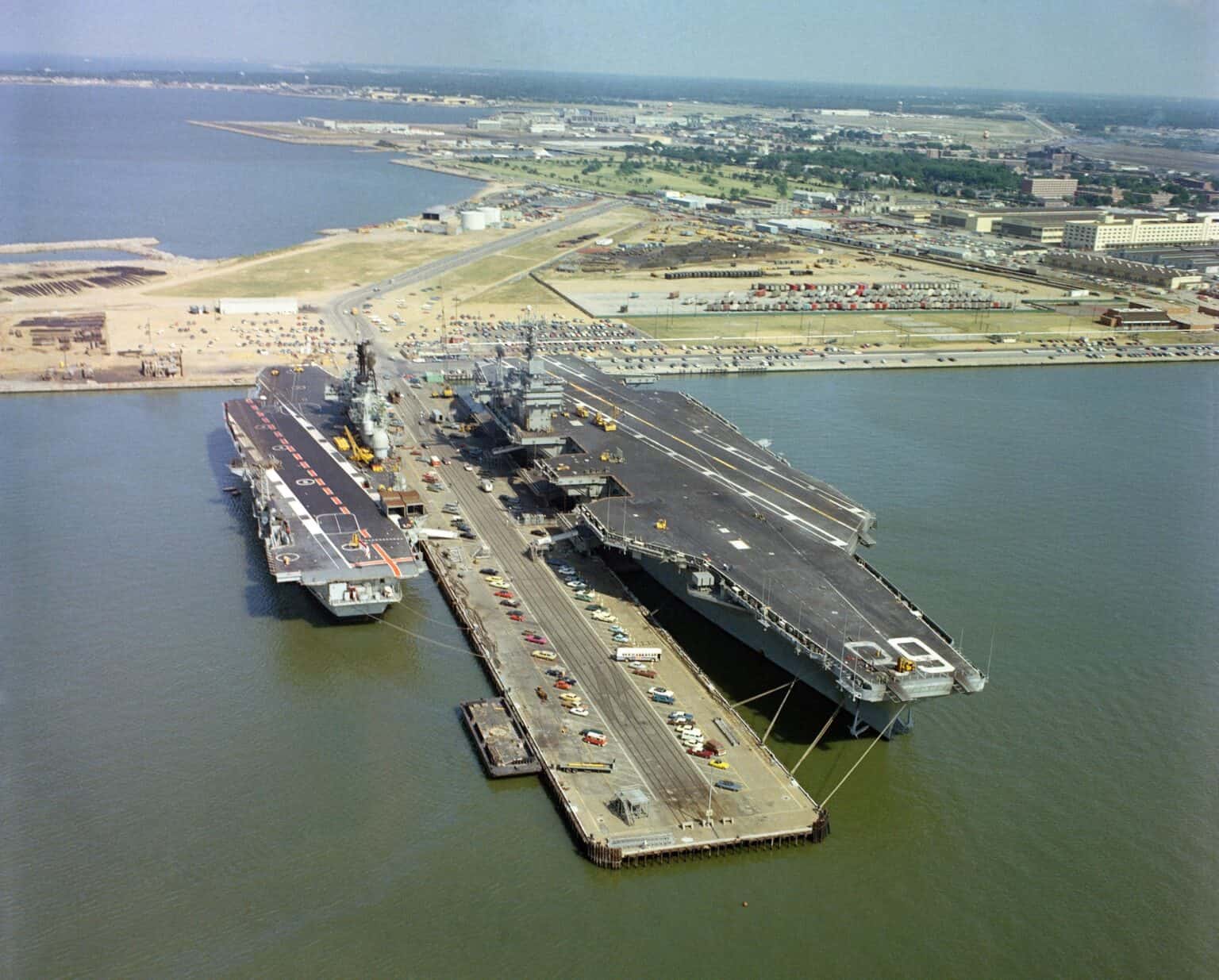 USS Nimitz and HMS Ark Royal tied up on either side of a pier at Naval Station Norfolk, seen from the air