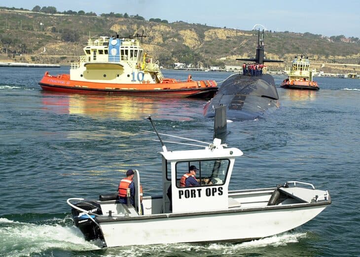 Ohio-class submarine leaving San Diego harbour with tugs and a port operations boat alongside