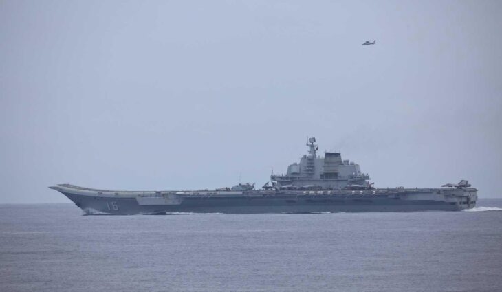 Chinese aircraft carrier Liaoning at sea with a Z-9 helicopter overhead