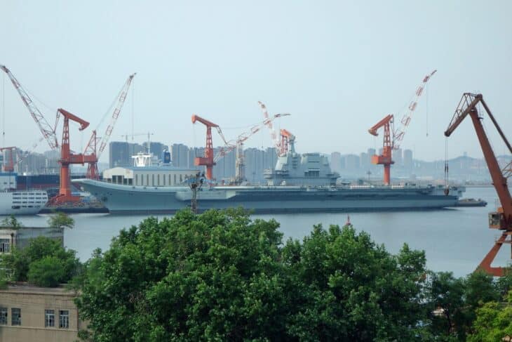 Chinese aircraft carrier Shandong at the Dalian shipyard in 2019, surrounded by cranes