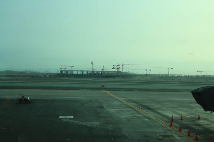 Part of the airfield at Jorge Chávez International Airport in Lima, with taxiway markings and construction cranes in the distance